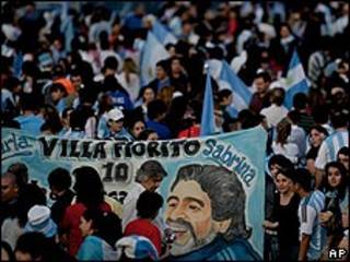 Seguidores de Argentina sostienen un cartel con la imagen de Maradona.