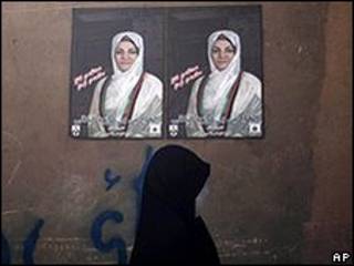 Mulher passa em frente a cartaz de campanha de Fauzia Galani, em Herat