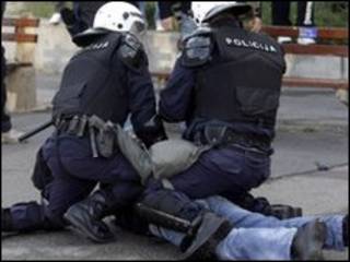 Manifestante é contido por policial em Belgrado