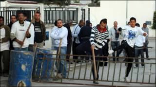 Người dân trang bị gậy gộc đứng chờ bên ngoài trạm kiểm soát vào Tunis