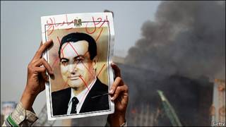 Manifestante con una foto tachada de Mubarak
