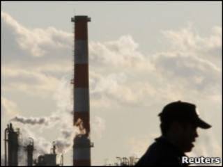 Japonês passa em frente a chaminé de fábrica nos arredores de Tóquio