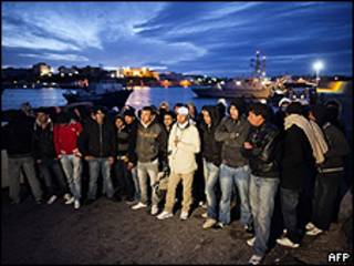 Imigrantes aguardam transporte para centro de triagem em Lampedusa (AFP)