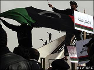 Manifestantes com uma bandeira antiga da Líbia em um prédio de Benghazi (Reuters)