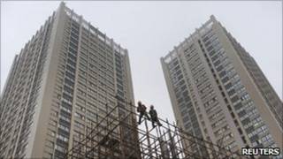 Двое китайских рабочих на фоне стройки