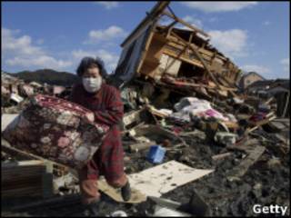 Sobrevivente do tsunami recolhe pertences de casa destruída