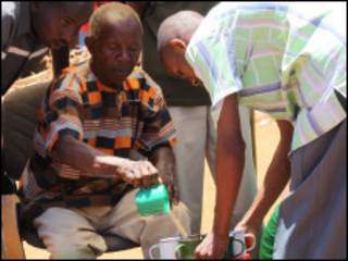 Curandeiro tradicional serve sua célebre poção a um de seus inúmeros fiéis ( David Wambundo - BBC)
