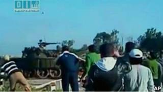 Толпа наблюдает, как человек бросает камень в танк в Дараа