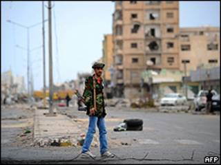 Rebelde em frente a prédio destruído na rua Trípoli, na cidade de Misrata (AFP/Getty)