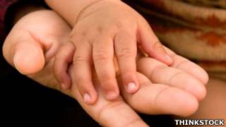 La mano de una bebé descansa sobre la de una mujer
