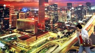 北京街頭民眾走過一幅以中心商業區夜景為題的巨型廣告(資料圖片)