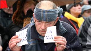 Латвия: человек разрывает флажок с надписью "Новый сейм"