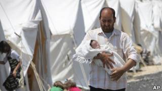 Refugiado carrega bebê em acampamento na cidade turca de Boynuyogun. Foto: AP