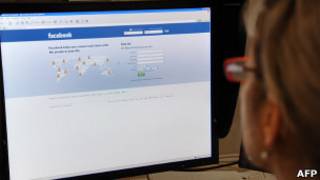 Usuária observa tela com a página inicial do Facebook