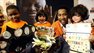 Crianças com cartões posam ao lado do neto de Mandela, Ndaba (Foto: AFP)