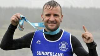Rob Sloan mostra medalha recebida após a prova