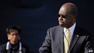 Ông Herman Cain phát biểu tại Atlanta hôm 3/12 trong khi vợ ông, bà Gloria đứng nhìn