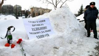 Плакат, цветы и бутылка шампанского, оставленные протестующими против полицейского насилия в Казани