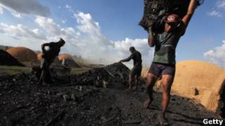 Trabalhador leva cesto de carvão vegetal produzido a partir de madeira retirada ilegalmente da Floresta Amazônica (Foto: Getty Images)