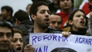 Manifestante pró-Lugo carrega cartaz em defesa da reforma agrária em protesto em Assunção (AP)