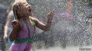 کودکی که با آب بازی تلاش می کند خود را خنک کند