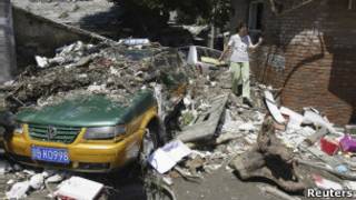 Moradora de Pequim tenta desviar de destroços deixados pela enchente (Reuters)