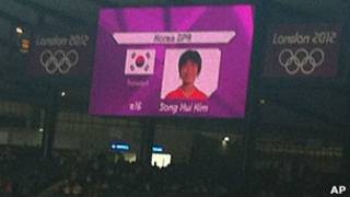 Bandera de Corea del Sur al lado de una jugadora de Corea del Norte