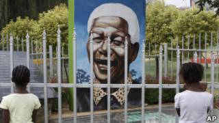 Crianças olham para retrato de Mandela em m parque em Soweto (foto: AP)