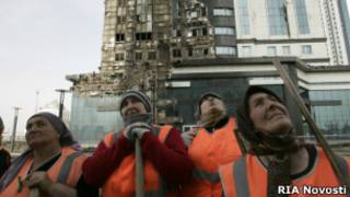 Рабочие у сгоревшего комплекса в Грозном