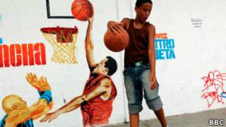 Menino brinca ao lado de grafite que mostra Chavez jogando basquete
