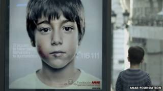 Un niño mira el cartel de la campaña