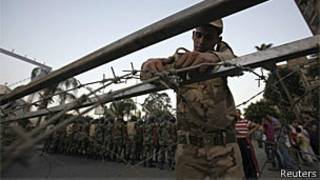 Militar coloca arame farpado enquanto soldados tomam posições em frente a manifestantes no Cairo (Reuters)