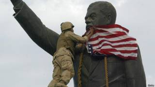 Soldado estadounidense pone bandera sobre la cabeza de la estatua de Sadam Hussein en Irak