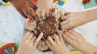 Manos de chicos en pastel de cumpleaños