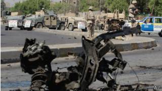 Мужчина смотрит на поврежденные автомобили после взрывов в Багдаде