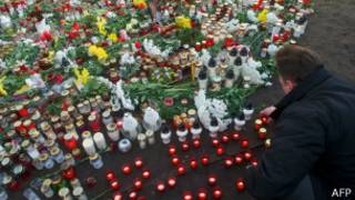 Мужчина зажигает свечу во время минуты молчания на месте трагедии в Латвии