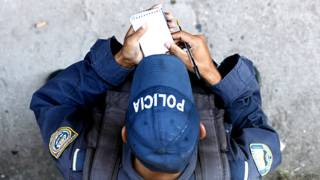 Oficial de policía en América Latina realizando anotaciones en una pequeña libreta