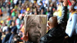 Hombre con un periódico con la imagen de Mandela