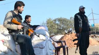 syrian fighters stand guard at a checkpoint