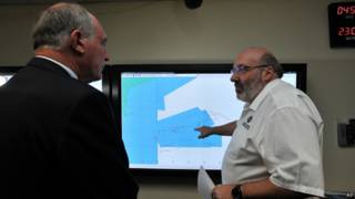 Mike Barton, que comanda a equipe de resgate australiana, mostra ao vice-premiê da Austrália, um mapa da região em que as buscas estão sendo realizadas no Oceano Índico (AP)