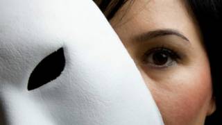 امرأة تضع قناعا مسرحيا أبيض أمام وجهها