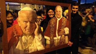 Fieis posam com quadro de João Paulo 2º e João 23 no Vaticano | Foto: BBC