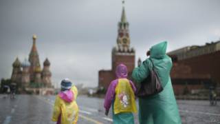 Холодный июнь 2014 года - туристы в плащах и куртках идут по Красной площади в Москве