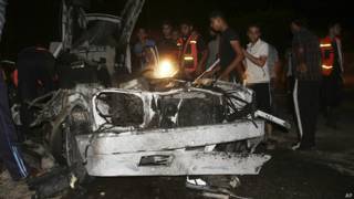 Palestinos con auto destruido en Rafah, Gaza