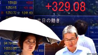 Ciudadanos japoneses frente a una pancarta con indicadores de mercado