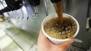 Una persona se sirve un vaso de Coca-Cola de una máquina.