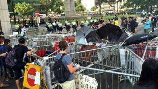 香港「佔領中環」行動參與者在幹諾道中中環段隔著剩餘路障與警察對峙 (BBC中文網圖片13/10/2014)