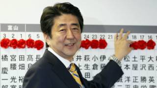 安倍晋三在给众议院选举当选者贴上红花标记