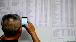 Homem olha lista de passageiros de voo desaparecido (foto: Getty)