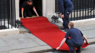 Workers roll out a red carpet